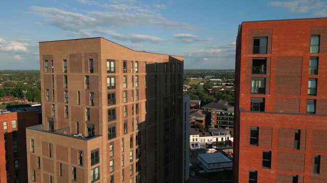 Modern brick apartment buildings overlook a suburban landscape under a partly cloudy sky.