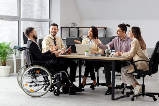Group of business people with man in wheelchair working at office