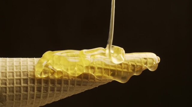 Sweet honey pouring on a crunchy waffle cone roll. 4K