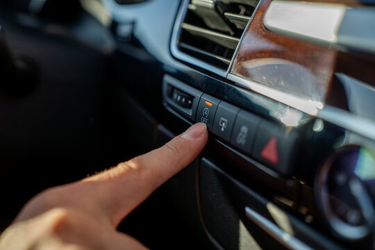 Finger presses start-stop system off button on car dashboard, disabling automatic engine stop and start function in vehicle interior.