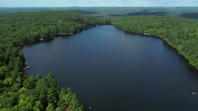 Aerial over Buckskin Lake above lakeside cottages along side expansive wilderness of crown land in Tory Hill, Halliburton Highlands East, Ontario, Canada. 