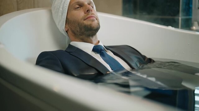 Portrait of confident businessman relaxing in a bathtub wearing suit suggesting surreal work life balance luxury lifestyle and unconventional success imagery