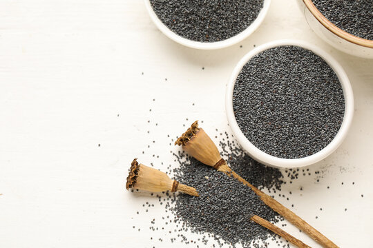 Bowl with poppy seeds on white wooden background, closeup