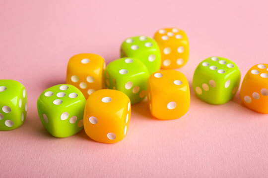 Different game dices on pink background, closeup