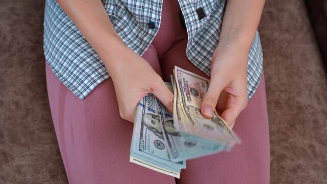 Closeup shot of female hands counting a stack of us dollar banknotes, highlighting concepts of salary, payment, personal finance, and wealth management, with fifty and hundred dollar bills visible