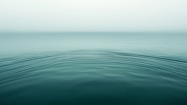 Tranquil expanse of water meets misty horizon, creating a serene and minimalist seascape, reflecting calmness