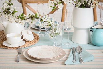 Fototapeta premium Elegant table setting with plates, glasses and blooming tree branches, closeup