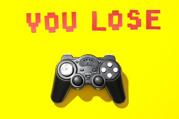 Text YOU LOSE with game pad on yellow background © Pixel-Shot