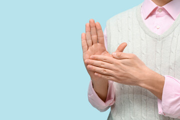 Young deaf mute man using sign language on blue background, closeup