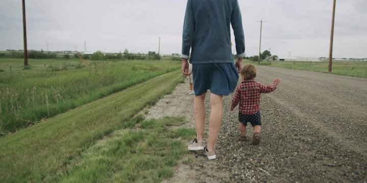 Mother and child walking a dog down a country road
