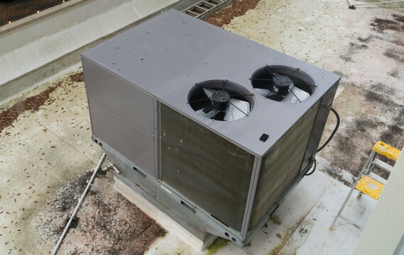 Large rooftop HVAC unit with dual fans provides essential climate control for commercial buildings. Industrial air conditioning system on a flat roof, awaiting maintenance or installation.