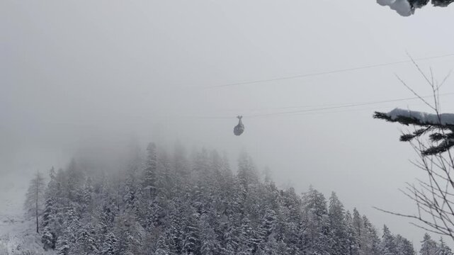 Cable car ascending through foggy winter landscape in Karwendel mountains near Mittenwald, Bavaria, Germany. Scenic alpine view with mist, snow and peaks, destination for travel, tourism and adventure