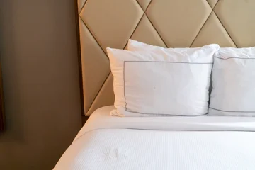 Fotobehang Hotel chique Clean white bedding and soft pillows on a luxurious bed with a stylish beige padded headboard, perfect for a comfortable hotel stay or modern home bedroom interior design.  © Michael