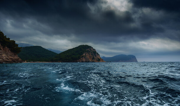 Dark moody seascape of the Petrovac bay with mountains and heavy storm clouds in Montenegro.