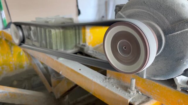 industrial belt and pulley system in motion on a construction machine, showing mechanical rotation and power transmission of heavy equipment for building and engineering projects