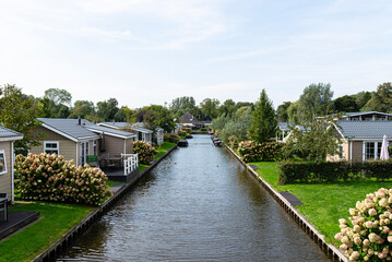 Fototapeta premium Giethoorn canal with holiday cottages, boats, and green lawns