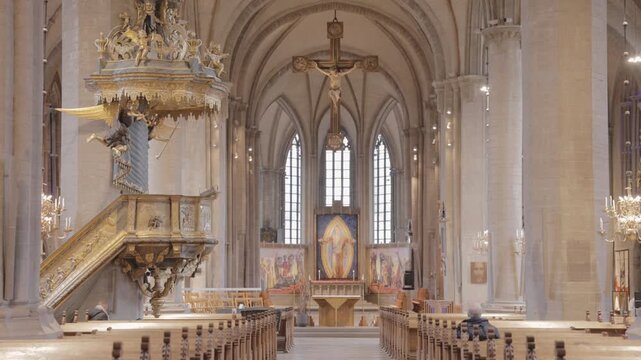 Static wide shot of historic cathedral interior with gothic architecture and golden pulpit in stockholm