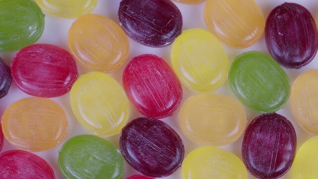 Assorted multicolored candies with sparkling sugar and glossy surfaces. Vibrant collection of hard candies in various hues with shiny textures and crystalline sugar details
