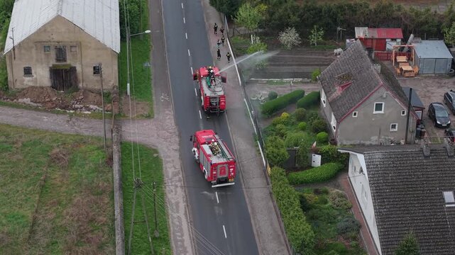Volunteer firefighters from a rural Polish village celebrating Wet Monday (Śmigus-Dyngus), joyfully splashing water and playing with local residents in a festive spring tradition