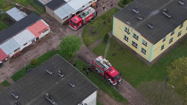 Volunteer firefighters from a rural Polish village celebrating Wet Monday (Śmigus-Dyngus), joyfully splashing water and playing with local residents in a festive spring tradition