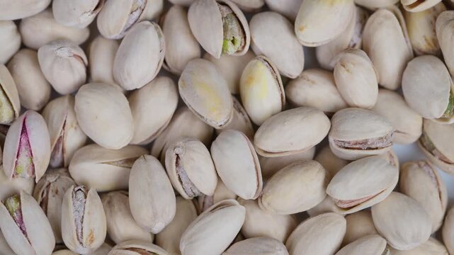 Salted pistachios with salt crystals. Closeup of salted pistachios in shells displayed naturally. Detailed image of salted pistachios with green kernels and coarse salt crystals