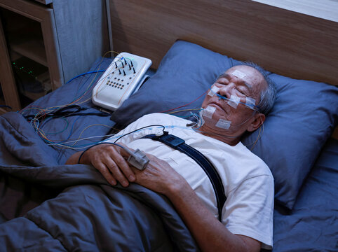 An elderly Asian man undergoes a sleep test.