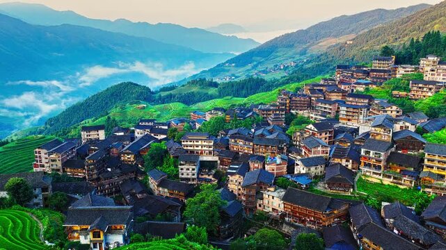 Aerial view of Longji rice terraces and a large traditional ethnic village on a mountain slope in Guilin, China.