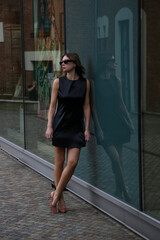Obraz premium Young Fashionable Woman in Black Mini Dress in City Street – Stylish Urban Street Style and Modern Lifestyle Concept