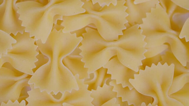 Pasta bow closeup. Close view of dry bowshaped pasta in pantry setting. Highresolution macro image showcasing uncooked bowtie pasta texture and pattern for culinary use