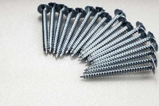 Zinc metal screws arranged in a semi circle on white plastic surface space for text