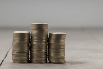 Side view of coin stacks: three piles with varying heights on neutral grey background.