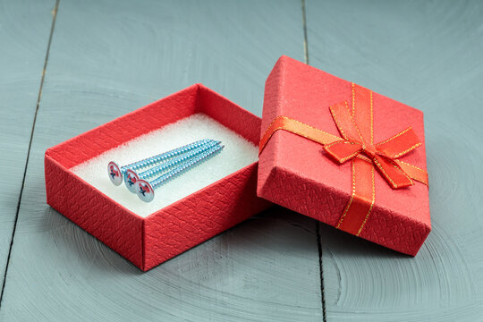 Three zinc screws in open red gift box, practical housewarming or renovation present