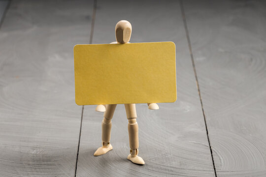 Artist mannequin presenting empty yellow placard, customizable communication and announcement