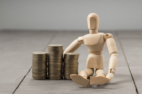 Artist mannequin sitting next to coin piles, financial growth and prosperity theme