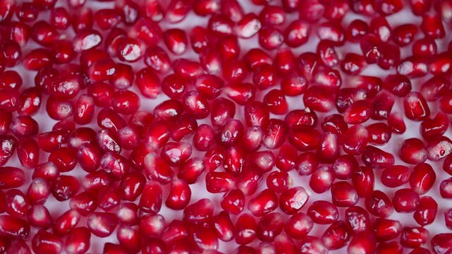 Vivid pomegranate imagery. Bright red seeds with reflective shine. Detailed image showcasing shimmering red pomegranate seeds in repeating pattern for various uses