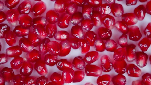 Closeup of glossy pomegranate arils with reflection. Photograph featuring densely packed red pomegranate seeds with shining surfaces and juicy appearance in studio setting