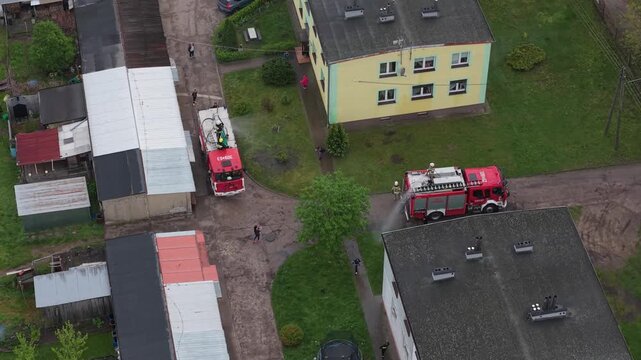 Volunteer firefighters from a rural Polish village celebrating Wet Monday (Śmigus-Dyngus), joyfully splashing water and playing with local residents in a festive spring tradition