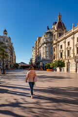 Obraz premium Female tourist strolling in front of Valencia City Hall on a sunny day, Spain.