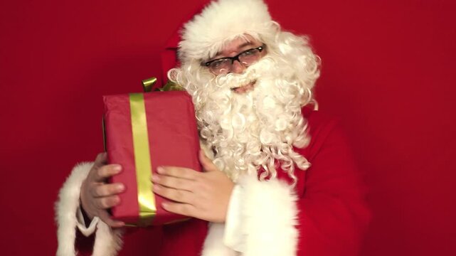 Santa Claus in red suit with white gloves carrying stacked gift boxes