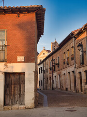 Fototapeta premium Old Spanish Village Street at Sunset - Charming narrow street in a historic Spanish town with brick architecture, cobblestones, and warm evening light.