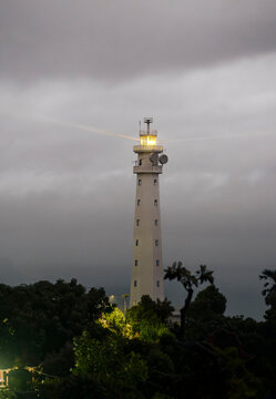 The lighthouse in Amed, Bali indonesia,  stands among green trees in the evening. The sky is soft and warm, creating a calm and peaceful view.
