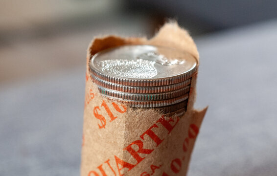 Close-up of a ten-dollar roll of shiny US quarters, partially unwrapped, symbolizing savings, finance, investment, and American currency. Perfect for financial concepts.