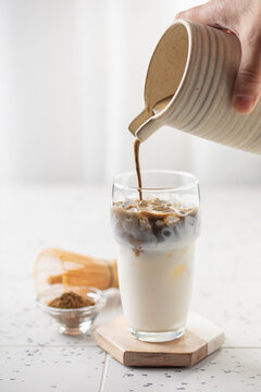 Preparing hojicha latte beverage. Iced  matcha latte tea. Vertical orientation.