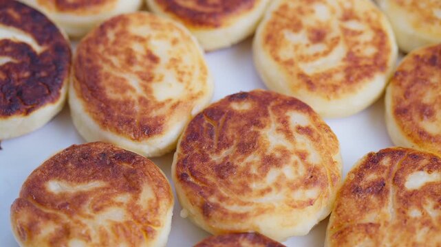 Mini cheese pancakes with crispy top, Closeup of golden cheese pancakes on white surface, Arrangement of golden cheese pancakes showcasing crispy crust and soft interior