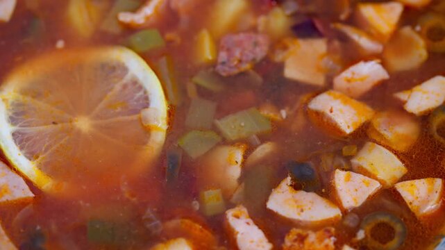 Lemoninfused smoked meat soup, Rustic bowl showcasing vibrant tomato base and garnish, Closeup of appetizing homemade solyanka filled with flavorful ingredients