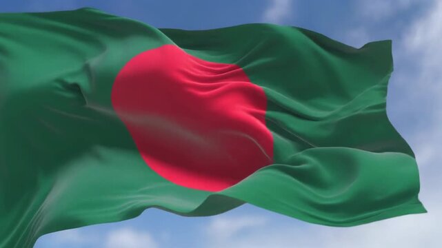 A green flag with a red circle waving in the wind against a blue sky with clouds, symbolizing national pride and patriotism outdoors