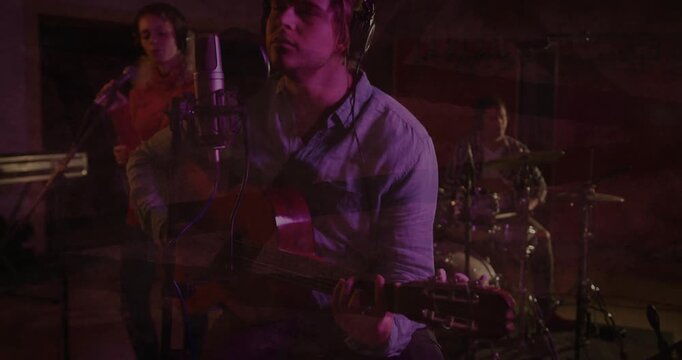 Lead singer-guitarist playing acoustic guitar, singing for recording, cam revealing ghosting band