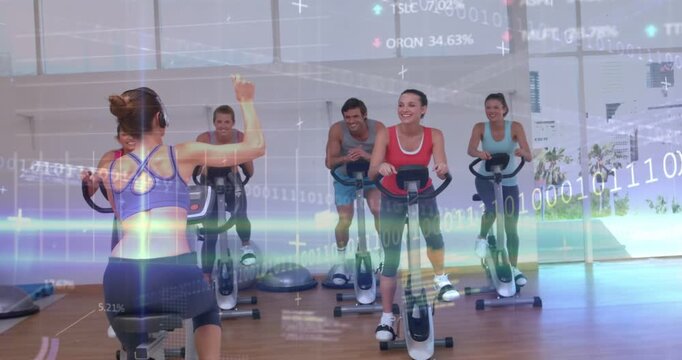 Coach raising arm cueing class, leading fitness ride, driving tempo while charts overlaying bikes