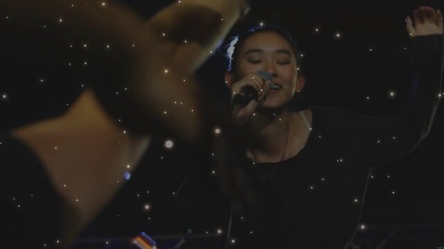 Vertical video: Singer singing leaning in music crowd urging fans reaching as mic and LEDs glinting
