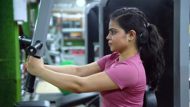 Indian Woman Performing Butterfly Exercise on Pec Deck Machine During Chest Workout in Modern Gym